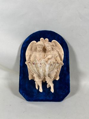 une image représentant une sculpture de deux anges posée sur un écrin en velours bleu