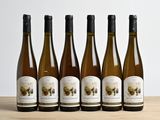 six bouteilles de vin sont alignées sur une table en bois