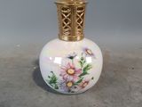 un petit vase blanc orné d'un couvercle doré et de fleurs
