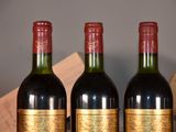 three bottles of red wine are lined up on a table