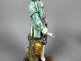 a figurine of a man with a hat and a bag