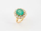 gros plan d'une bague avec une pierre verte entourée de diamants
