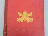 an old red book with a gold emblem on the cover