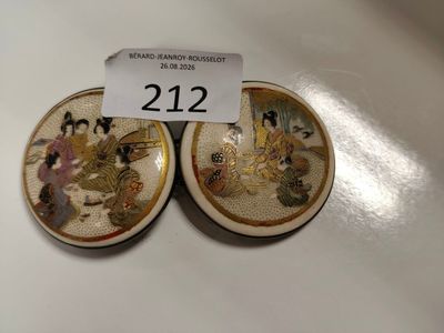 Deux petites assiettes ornées de peintures asiatiques sont posées sur une table.