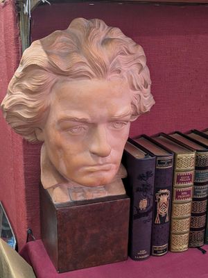 un buste d'homme assis sur une étagère avec des livres