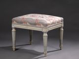 un repose-pieds rembourré dont l'assise est recouverte d'un tissu à motifs floraux