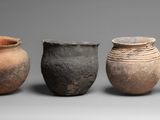 four clay pots are lined up in a row on a gray surface