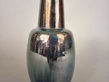 a silver and blue vase sitting on a white surface