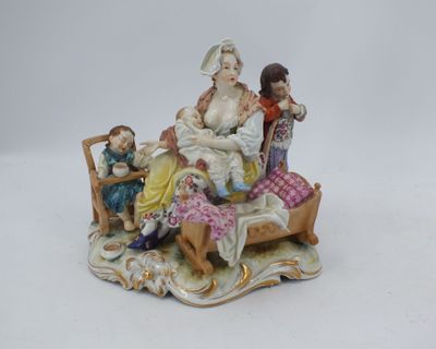 une figurine représentant une femme assise sur un lit avec deux enfants