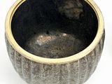 a black bowl with a gold rim on a white surface