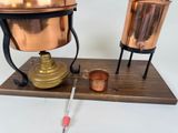 a copper pot and a copper cup on a wooden stand