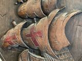 a wooden plaque with a ship carved into it