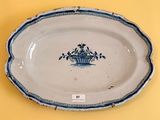 an old blue and white plate with a basket of flowers on it