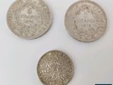 trois types différents de pièces d'argent sur une surface blanche