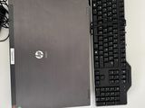 un ordinateur portable et un clavier posés sur un bureau, avec une souris et un casque