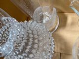 a glass pitcher sitting on a table next to other glassware