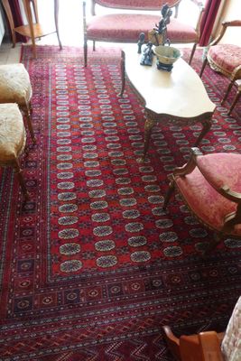 un salon avec un tapis rouge, des fauteuils et une table basse