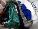 a pile of clothes sitting on top of a bed next to a pillow