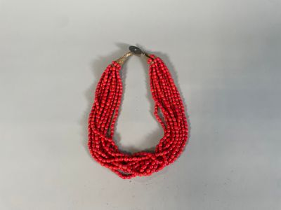 un gros plan d'un collier de perles rouges posé sur une surface blanche