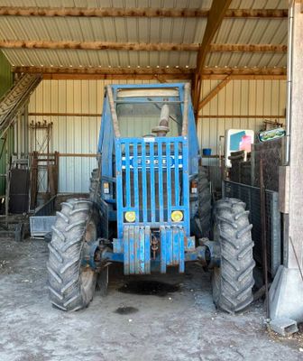 un tracteur bleu garé à l'intérieur d'un bâtiment