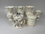 four white vases sitting next to each other on a table