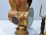 pair of antique brass gas masks and a candle holder on a white table