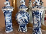 three blue and white vases sitting on a table next to a mirror