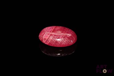 a close up of a red stone on a black surface