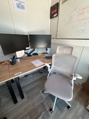 un bureau avec un ordinateur et une chaise devant un tableau blanc