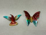 pair of colorful butterfly brooches on a white surface