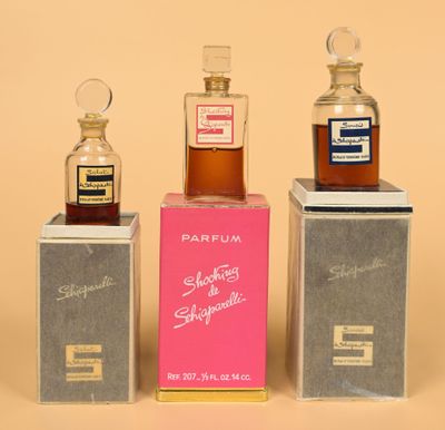 three small bottles of perfume sitting on top of boxes on a table