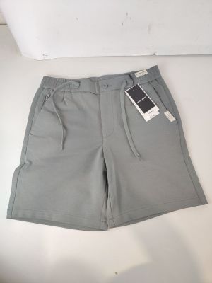 Le short est gris clair et comporte une petite poche sur le côté.