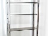 a metal shelf with glass shelves in the corner of a room