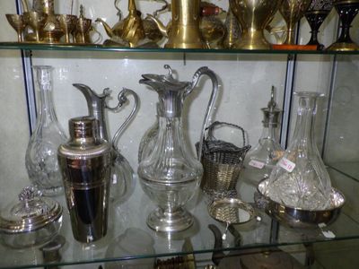 a glass shelf with a lot of silver vases on it