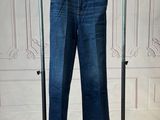 jeans hanging on a clothes rack in front of a white wall