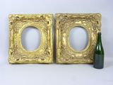 two gold picture frames with a green bottle next to them