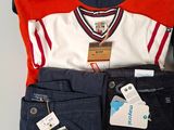 a pile of clothing that includes a polo shirt, pants, and a cell phone