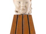 statue d'un garçon coiffé d'un chapeau, posée sur un morceau de bois