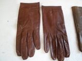 three pairs of brown leather gloves sitting on top of a white surface