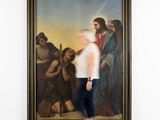man walking past a large painting of jesus in a museum