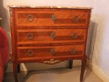 a wooden chest of drawers with marble top in a bedroom
