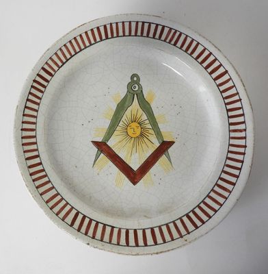 une assiette ornée d'un symbole maçonnique, posée sur une table