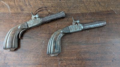 two old guns are sitting on a wooden table next to each other
