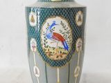 a blue vase with a bird on it sitting on a table