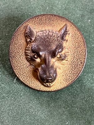 une photo d'une broche représentant une tête de loup sur un plateau