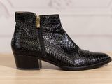 the black ankle boots are on a wooden table