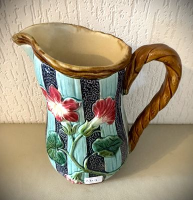 un petit pichet orné de fleurs, posé sur une table