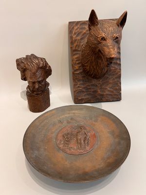 une assiette ornée d'une tête de chien, à côté d'un bol orné d'une tête de chien