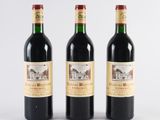 three bottles of red wine sitting next to each other on a white surface