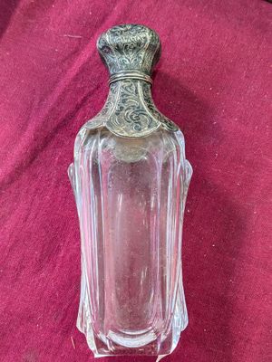 une petite bouteille en verre avec un bouchon argenté, posée sur un tissu rouge